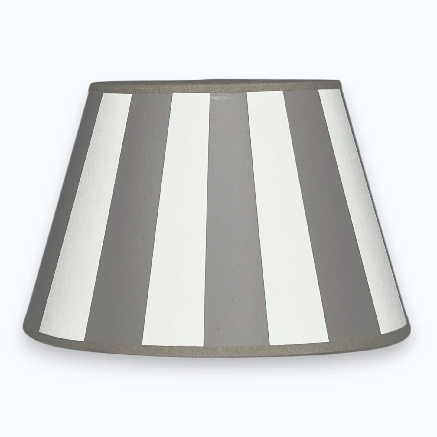 Ovaler Lampenschirm aus Stoff in Taupe und Weiß mit Streifendesign  auf hellem Hintergrund.