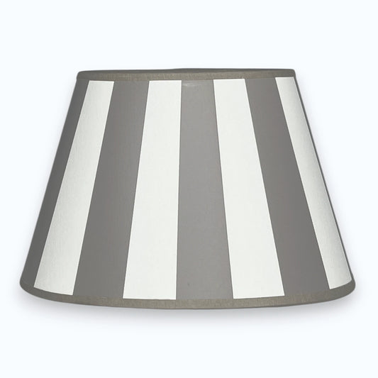 Ovaler Lampenschirm aus Stoff in Taupe und Weiß mit Streifendesign  auf hellem Hintergrund.