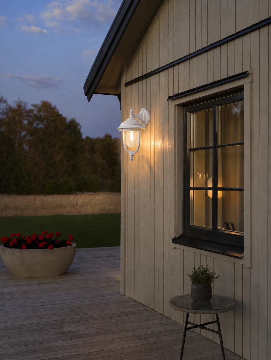 Klassische Außenwandleuchte Parma in Weiß mit warmweißem Licht an einer hellen Holzfassade im Landhausstil bei Dämmerung