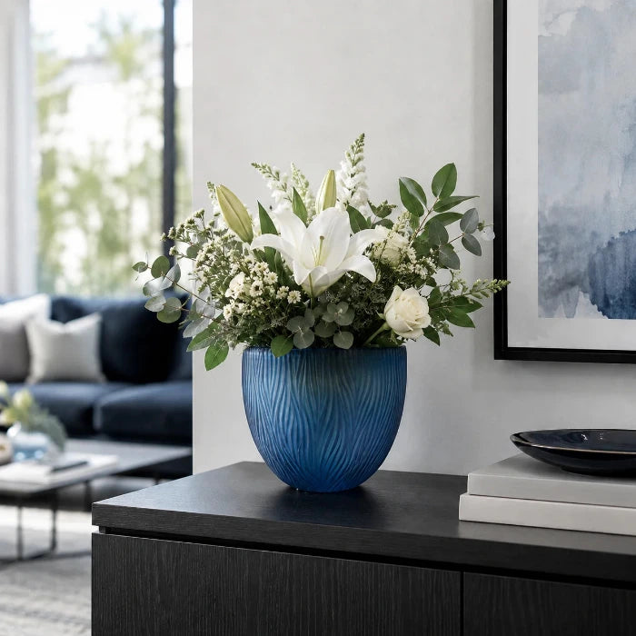 Blaue Glasvase von Sompex mit weißen Blumen auf einem Sideboard in einem modernen Wohnzimmer