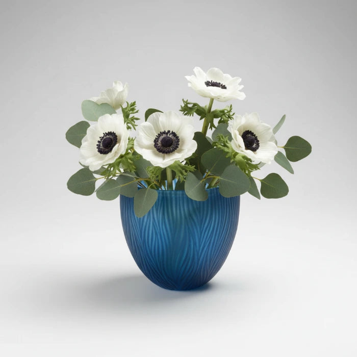 Blaue Glasvase von Sompex mit Wellenmuster, mundgeblasen und handgeschliffen, freigestellt auf grauem Hintergrund mit blumenstrau