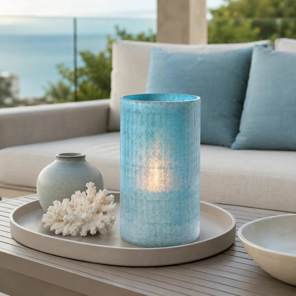 Blaue Glasvase in Vintage-Optik mit Kerzenlicht auf einem dekorierten Tablett auf einer modernen Terrasse