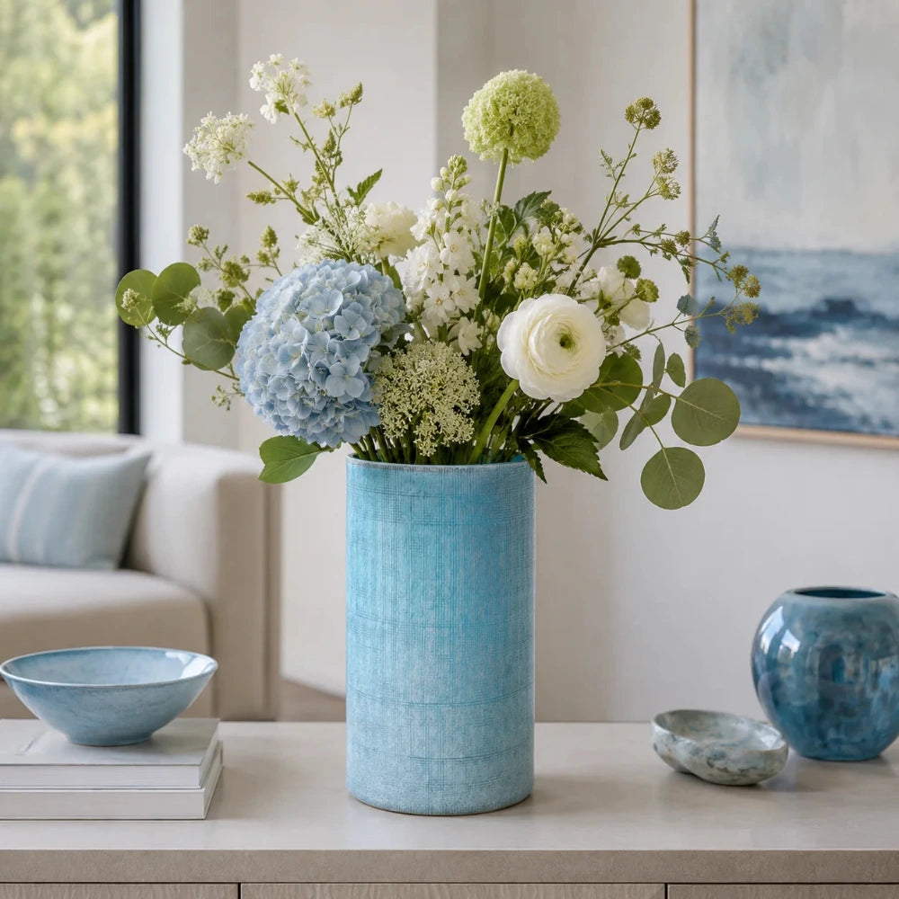 Blaue Blumenvase aus Glas in Vintage-Optik mit frischem Blumenstrauß in einem modernen Wohnzimmer