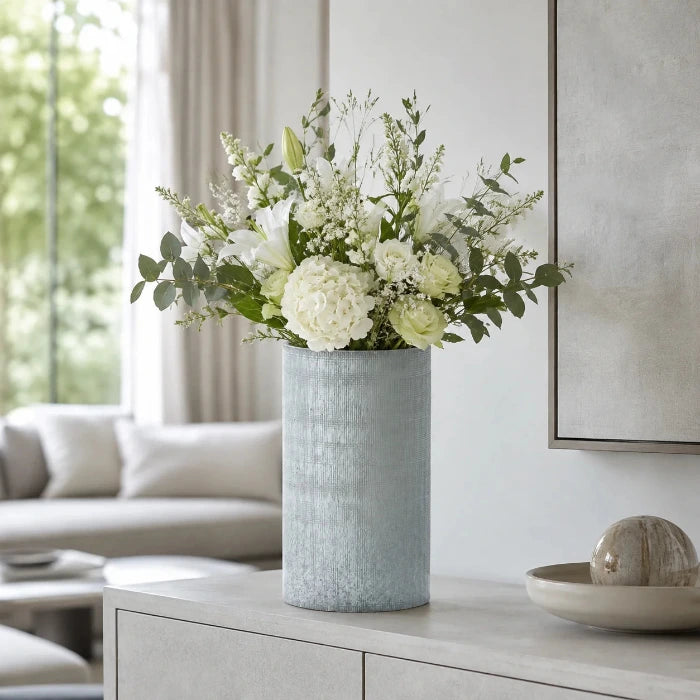 Graue Blumenvase in Vintage-Optik mit Blumenstrauß auf einem Sideboard im modernen Wohnzimmer