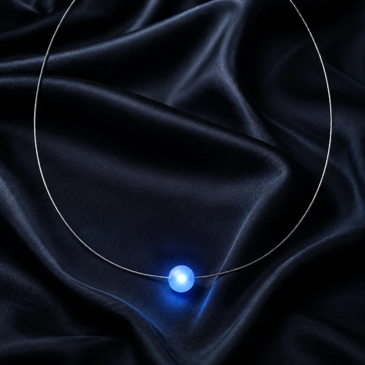 Firejewel LED-Halskette mit blau leuchtender Milchglaskugel luxuriös präsentiert auf schwarzer Seide