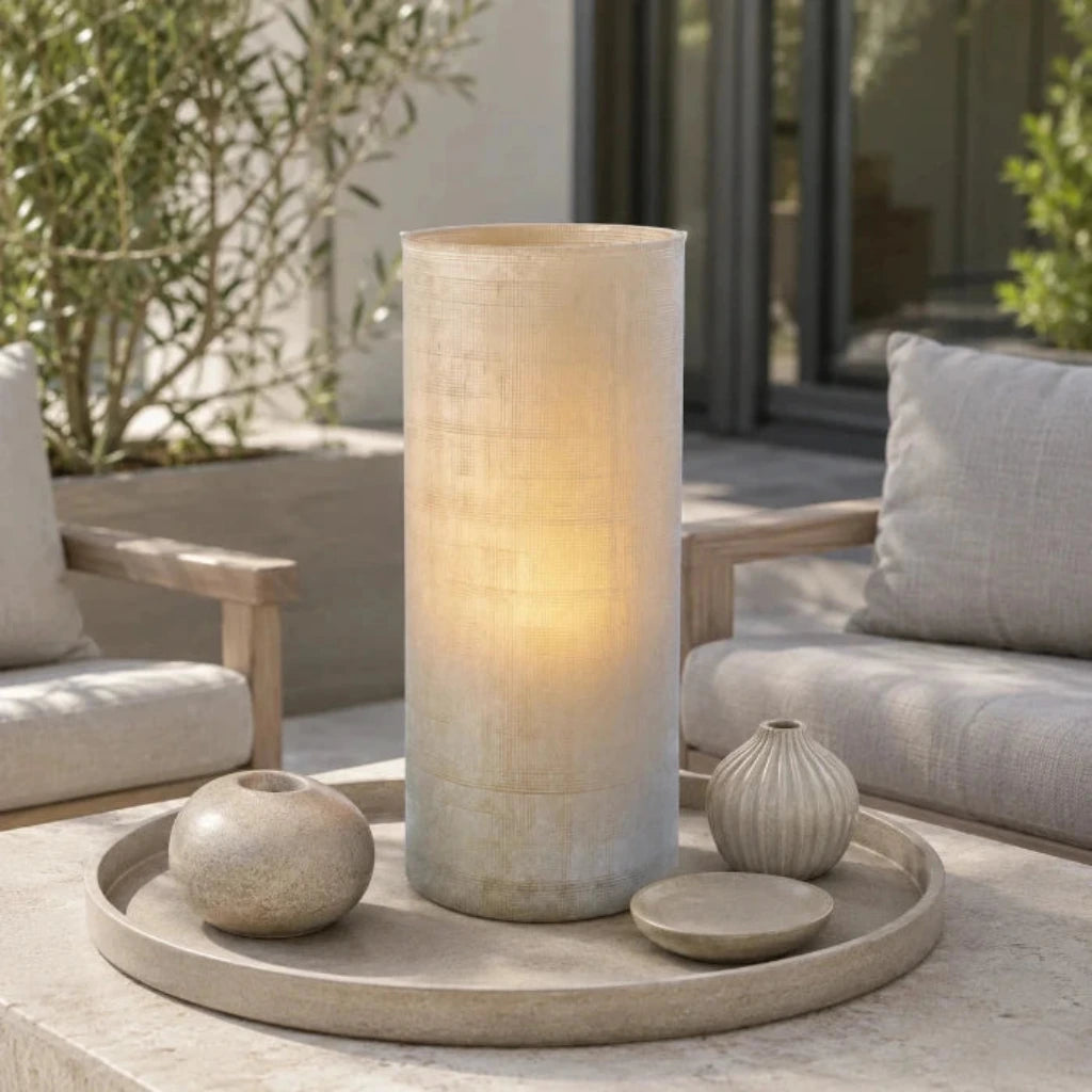 Beige Glasvase mit sichtbarem Kerzenlicht auf einem Dekotablett auf einer modernen Terrasse