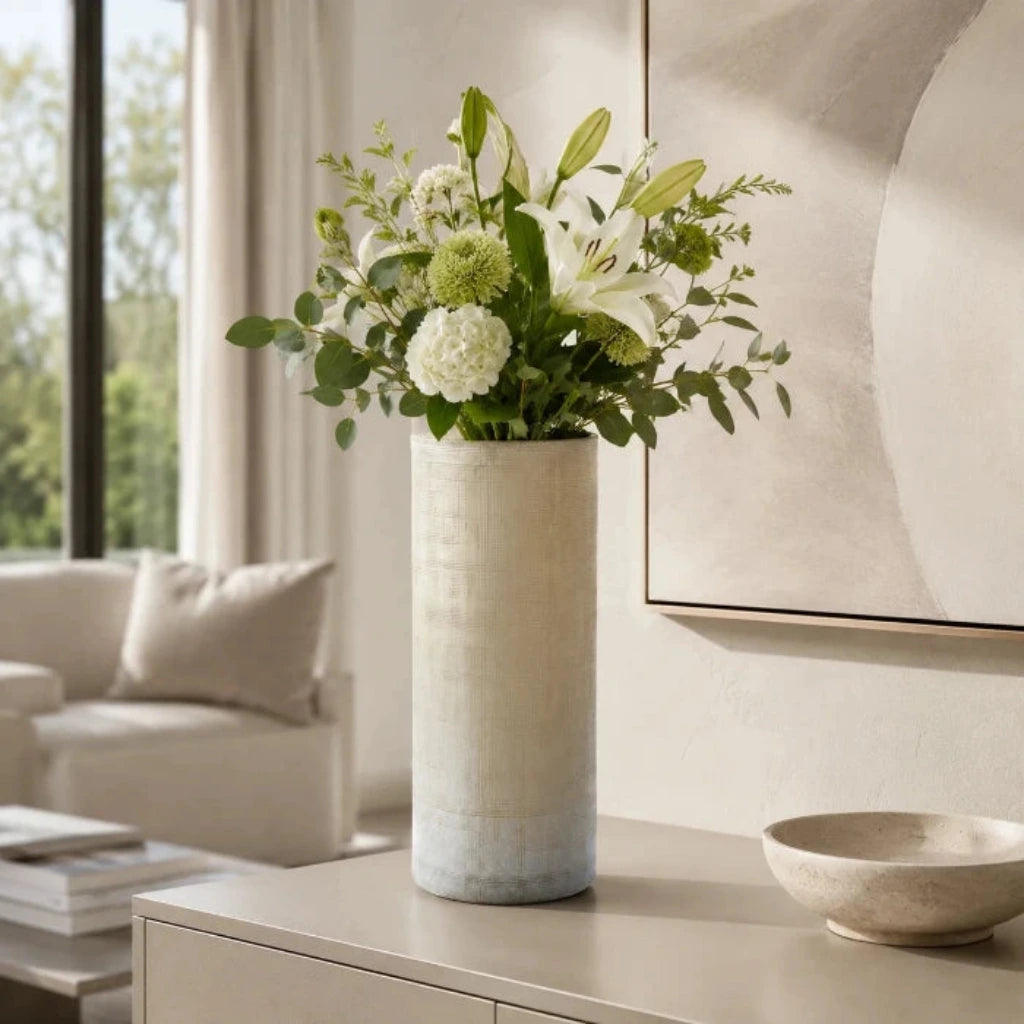 Hohe beige Glasvase mit Blumenstrauß auf einem Sideboard in einem modernen hellen Wohnzimmer