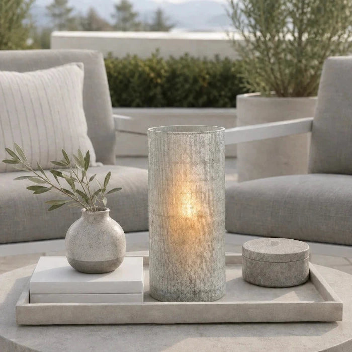 Graue Blumenvase Ashley aus strukturiertem Glas mit sichtbarem Kerzenlicht auf einem Dekotablett auf moderner Terrasse