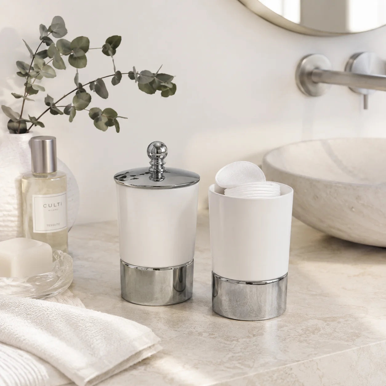 Moderne weiße Keramik-Kosmetikdose mit Chromdetails und Wattepads auf einem hellen Badezimmer-Waschtisch dekoriert.