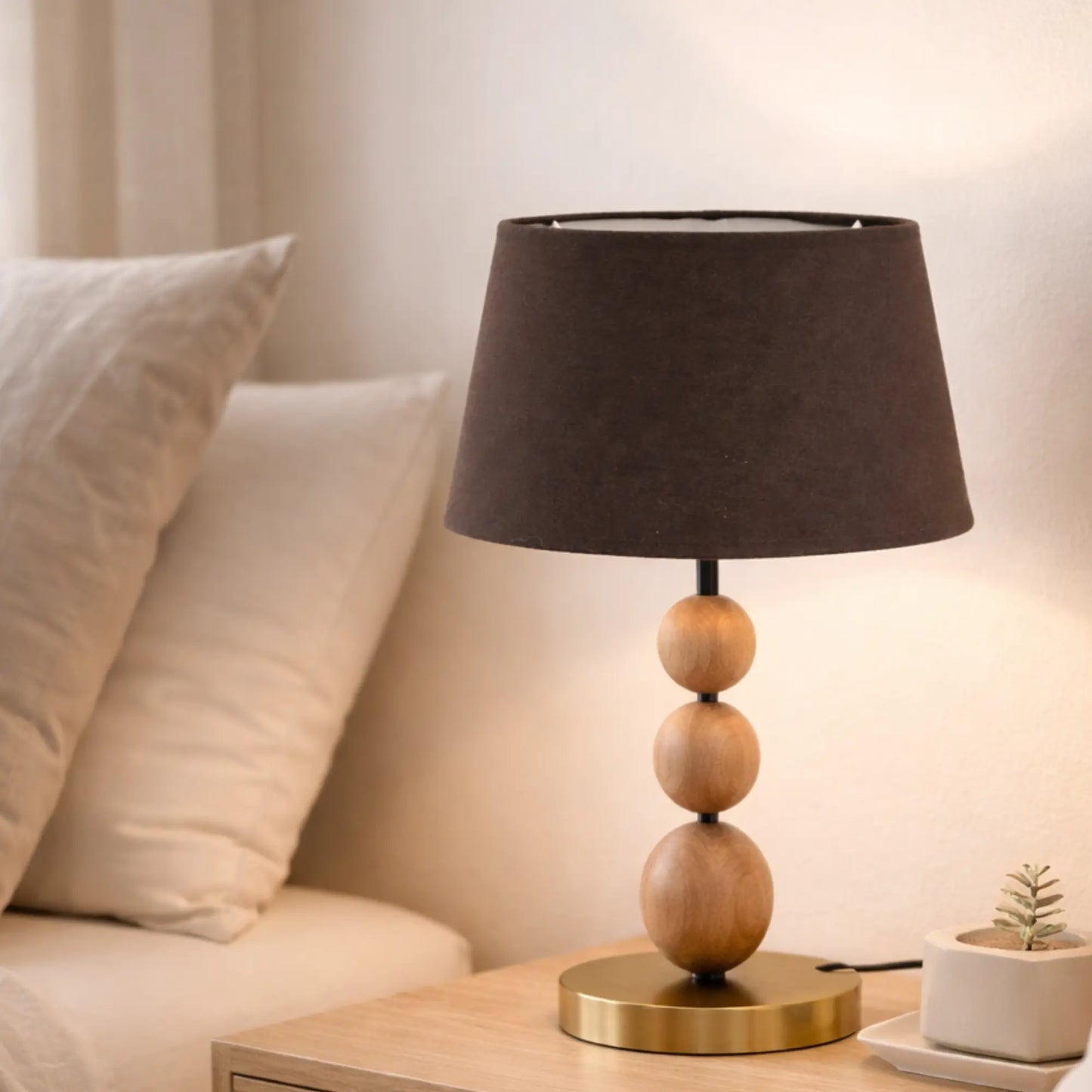 Brauner Lampenschirm aus Baumwolle (Artikel 5825-883) montiert auf einer Nachttischlampe mit Holzfuß und goldenem Sockel neben einem Bett im Schlafzimmer.