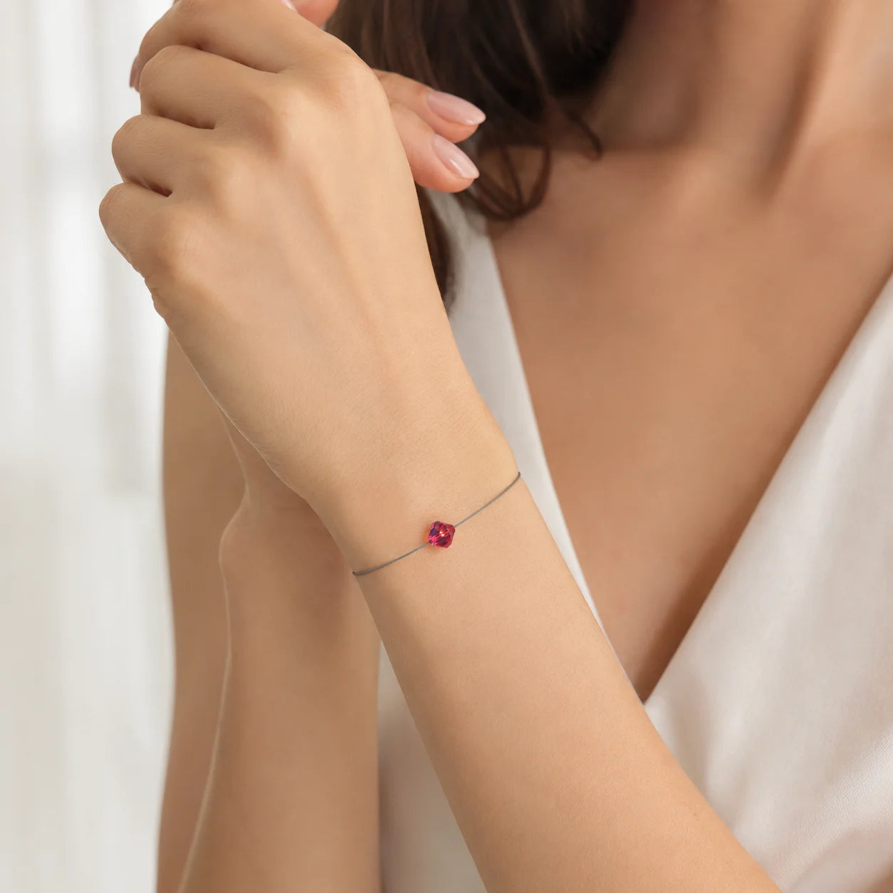 Frau trägt ein filigranes LED-Armband mit kleinem roten Swarovski® Kristall in Bicone-Form