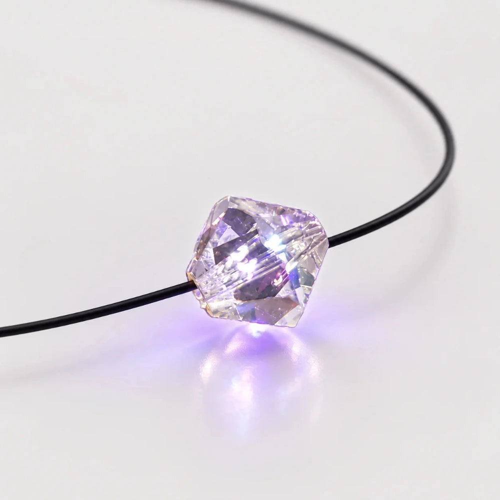 Transparenter facettierter LED-Kristall an schwarzem Kabel mit leuchtendem Licht als dekorative Halskette  Beleuchtung.