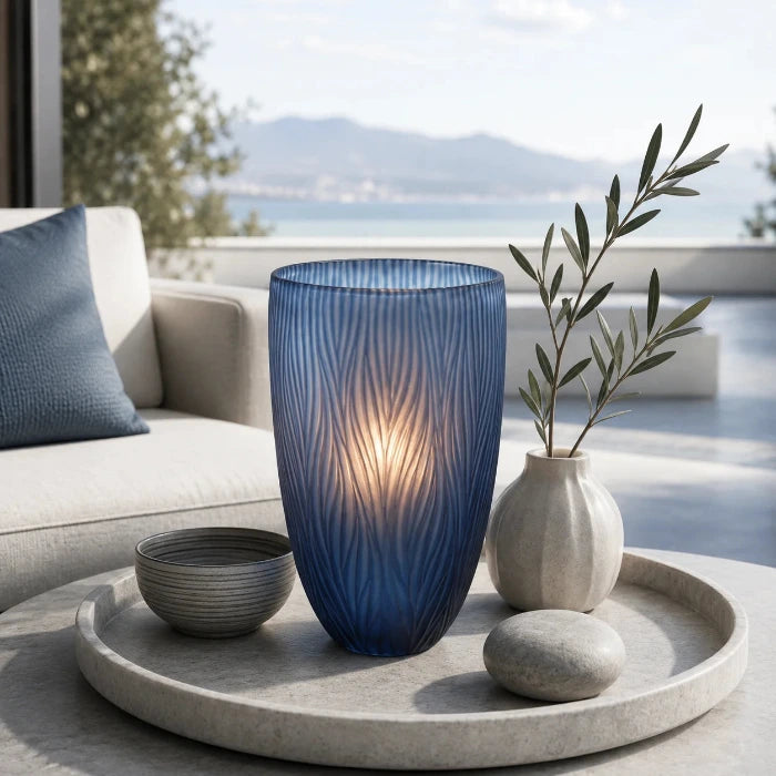 Blaue Glasvase Dinah mit leuchtender Kerze auf einem Dekotablett auf einer modern eingerichteten Terrasse