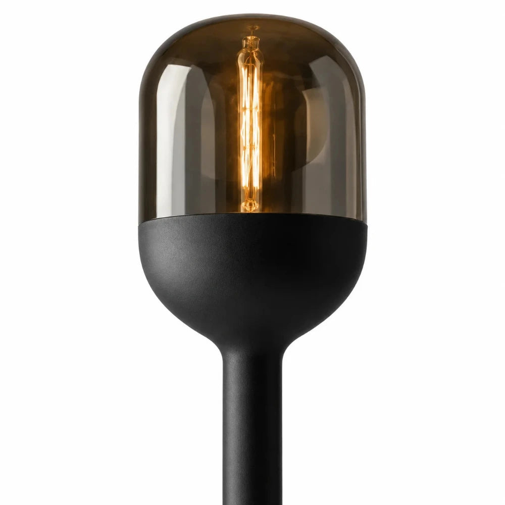 Detailansicht der Sompex DOME Stehlampe mit amberfarbenem mundgeblasenem Glas, schwarzem Lampenkopf und warm leuchtendem Leuchtmittel.