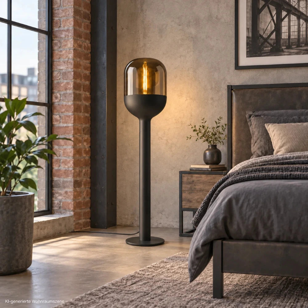 Sompex DOME Stehlampe mit schwarzem Gestell und amberfarbenem Glas in einem modernen Schlafzimmer im Industrial-Stil neben dem Bett.