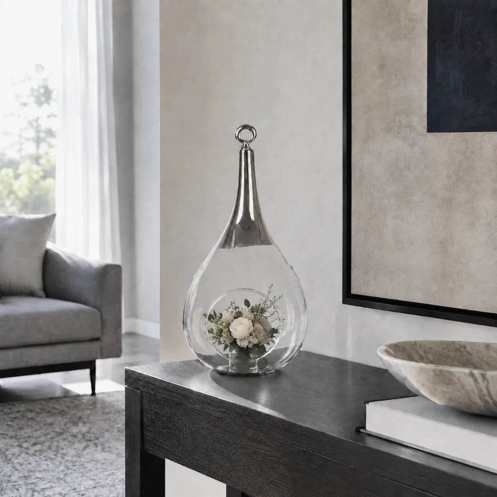 Sompex Taura Hängewindlicht aus Glas und Chrom mit kleinem Blumenarrangement auf einer schwarzen Konsole im Wohnzimmer