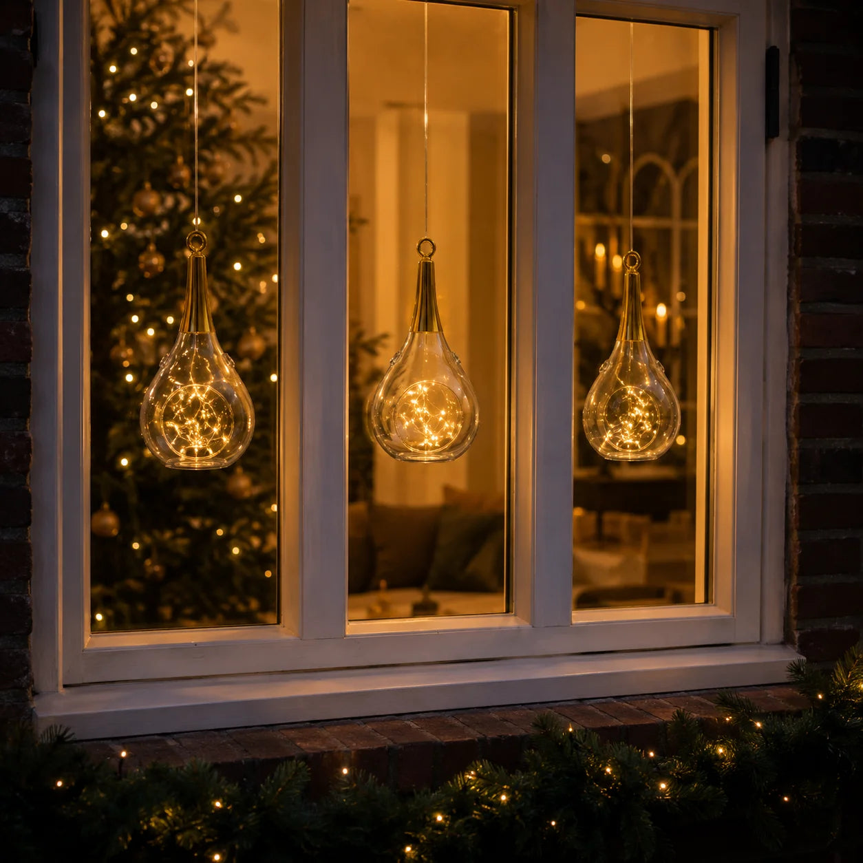 Drei Sompex Taura Gold Hängewindlichter mit warmen LED-Lichtern als Weihnachtsdekoration am Fenster