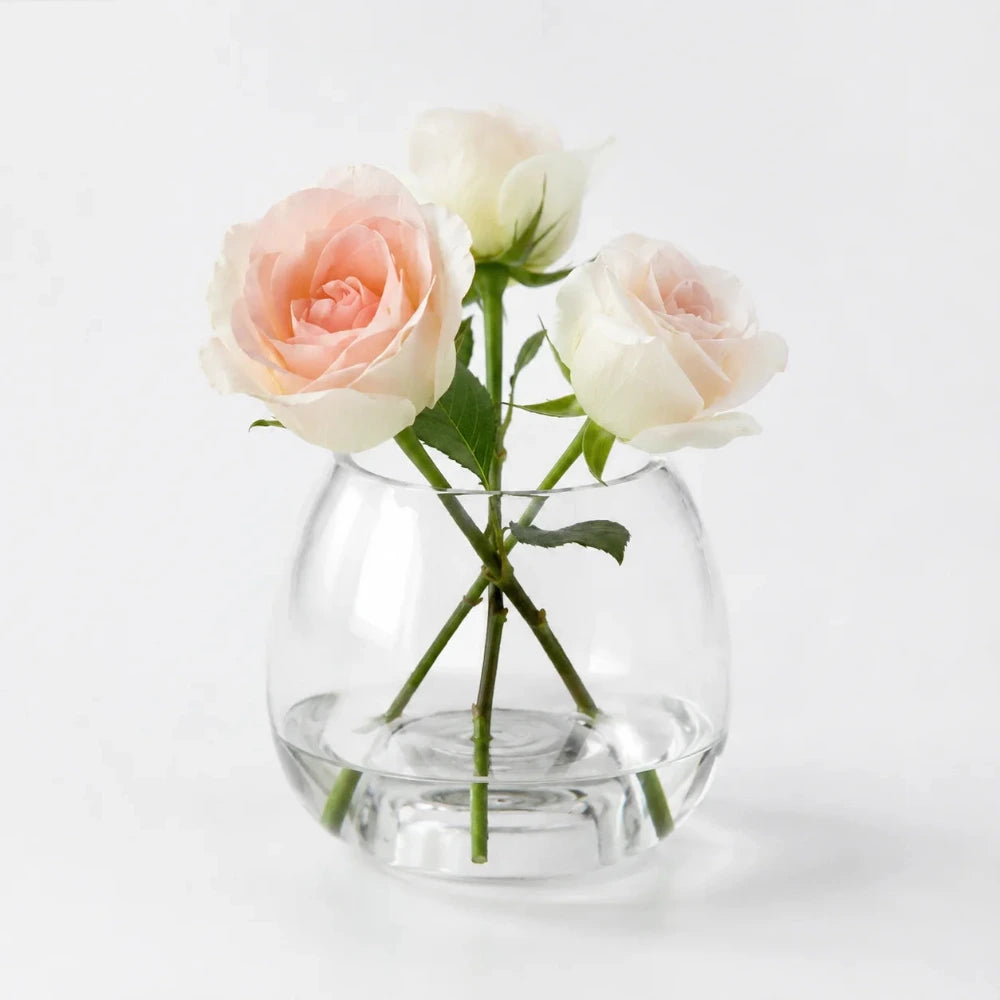Transparente kleine Blumenvase aus Glas mit rosa und weißen Rosen dekoriert