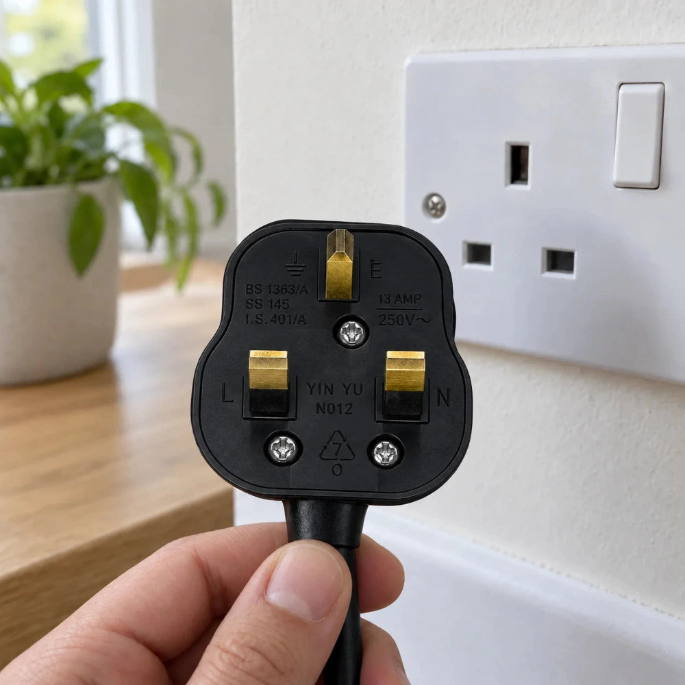 Schwarzer UK-Stecker Typ G vor einer britischen Steckdose mit drei rechteckigen Öffnungen in einem hellen Innenraum.