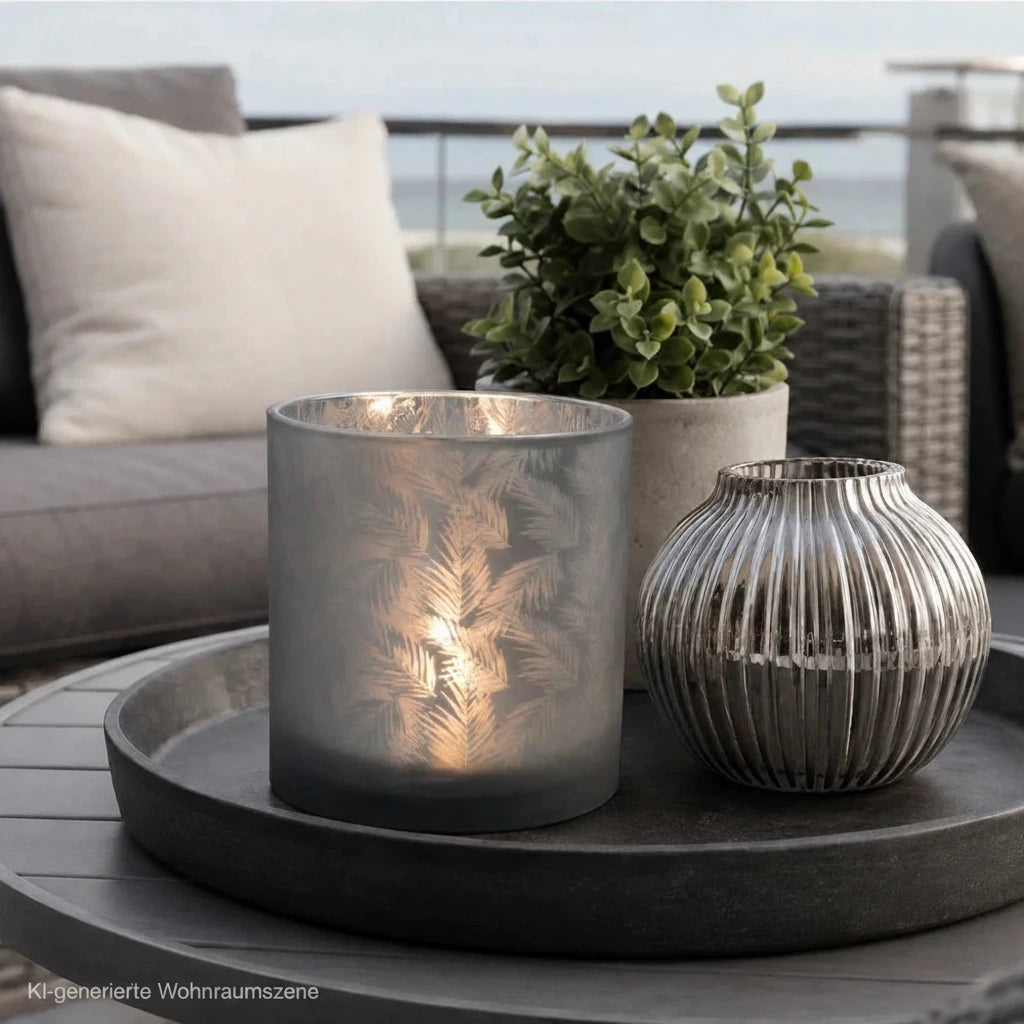 Grau-silbernes Glas-Windlicht mit Farnmuster und Kerzenlicht auf einem Tablett auf moderner Terrasse